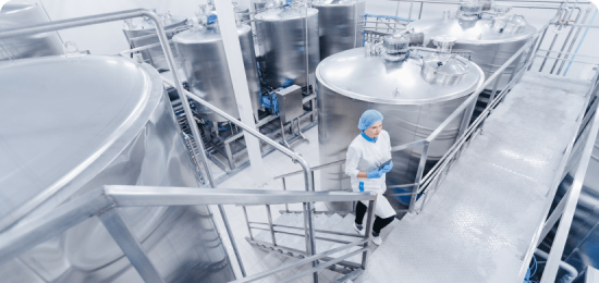 Female worker operator in uniform holding computer tablet near food factory production line for Aseptic Processing and Packaging Systems.