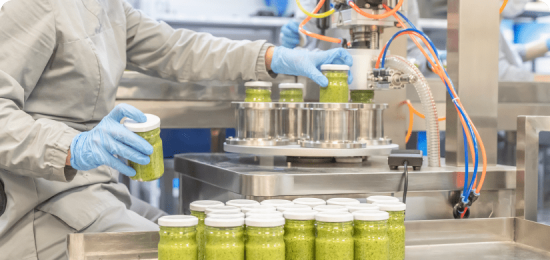 Plant worker running machine for capping pesto bottles.