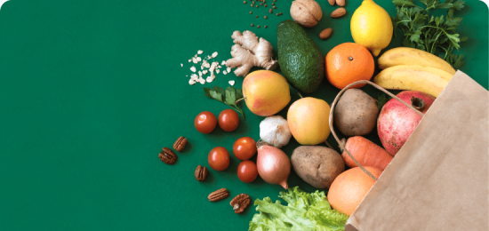 Paper bag holding fruits, veggies, and nuts.