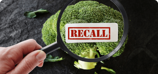 Piece of broccoli under magnifying glass with rendered recall label on broccoli.